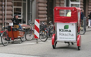 Die Rikscha der Rikscha-Aktion mit dem Logo der Kampagne "Ich mach Klima" auf der Rückseite.