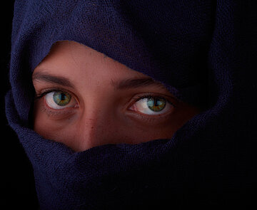 Frau mit Kopftuch und Schleier vor Gesicht, nur Augenpartie ist zu sehen. 