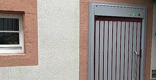 Blick auf Hauswand mit WC-Anlagen-Tür