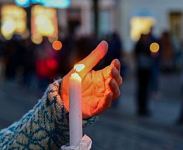Bei der Mahnwache "Karlsruhe steht zusammen: Solidarität mit der Ukraine!" am 6. März auf dem Marktplatz wird eine brennende Kerze hochgehalten.