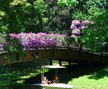 Das Bild zeigt eine Brücke über dem Stadtgartensee mit einer Gondoletta im Zoologischen Stadtgarten. 