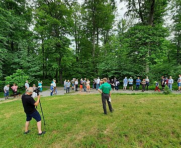 Das Bild zeigt Menschen bei einer Veranstaltung im Wald.
