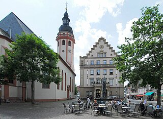 Tische und Stühle stehen auf dem Marktplatz Durlach mit dem Kirchturm im Hintergrund.