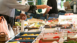Das Bild zeigt einen Marktstand mit Gemüse und steht symbolisch für den Wochenmarkt Rüppurr