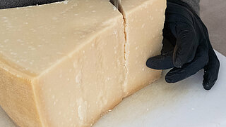 Das Bild zeigt einen Mann, der frischen Käse hobelt.