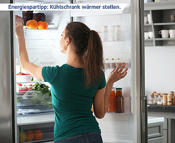 Frau steht vor offenem Kühlschrank. Auf einem Text steht Energiespartipp: Kühlschrank wärmer stellen