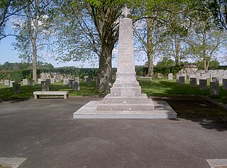 Das Bild zeigt ein weißes Denkmal mitten auf dem Friedhof