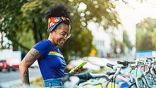Eine junge Frau bucht mit ihrem Smartphone ein E-Bike