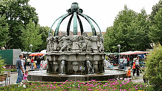 Das Bild zeigt den Krautkopfbrunnen auf dem Gutenbergplatz, welcher als Wahrzeichen der Karlsruher Weststadt gilt.