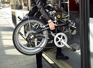 Das Foto zeigt einen Fahrgast mit Fahrrad beim Einstieg in einen Bus.  