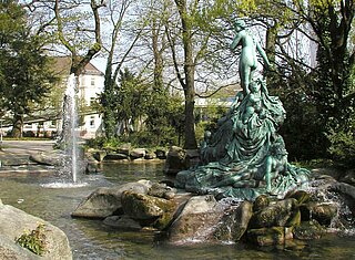 Das Bild zeigt die Bronzefigur der Nymphen am Brunnen des Nymphengartens. 