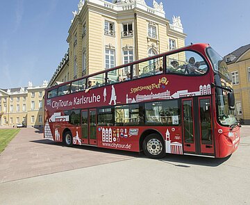 Das Bild zeigt einen HopOn/HopOff Bus vor dem Karlsruher Schloss.