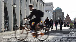 Das Foto zeigt einen Fahrradfahrer in der Innenstadt als Symbolbild für den Öffentlichen Raum und Mobilität Innenstadt