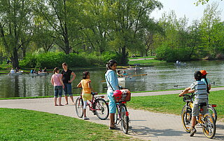 Das Bild zeigt Menschen auf Fahrrädern und Spaziergänger auf dem Weg am See der Günther-Klotz-Anlage