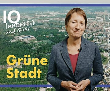 Bürgermeisterin Bettina Lisbach steht vor einem Luftbild der Stadt Krlsruhe