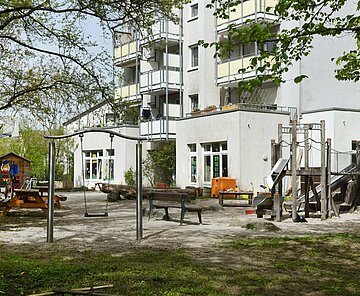 Gebäudeansicht Kita Ellmendinger Straße mit Spielplatz im Vordergrund