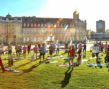 Personen bei Sportübungen vor dem Schloss Karlsruhe