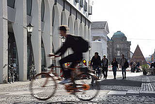 Das Foto zeigt einen Fahrradfahrer in der Innenstadt als Symbolbild für den Öffentlichen Raum und Mobilität Innenstadt
