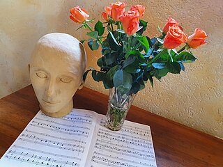 Musiknoten mit Rosen und Skulptur