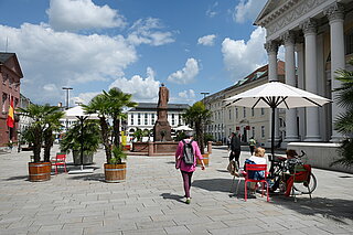 Marktplatz mit Palmen, Stühlen und Schirmen