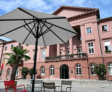 Sitzmöglichkeiten unter Sonnenschirmen umgeben von Palmen auf dem Marktplatz vor dem Rathaus