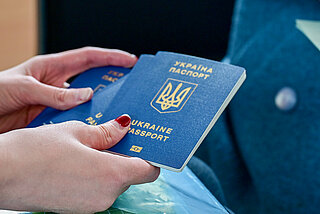 Ukrainehilfe: Das Bild zeigt Hände in Nahaufnahme, die einen ukrainischen Pass halten.