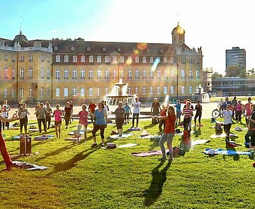 Menschen beim Sport auf der Wiese vor dem Karlsruhe Schloss
