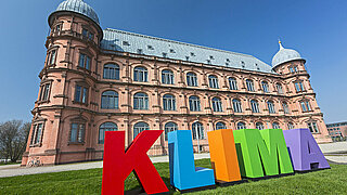 Für die Klimaaktionstage wurden große, plastische Buchstaben aus buntem Sperrholz angefertigt. Zusammengesetzt bilden sie das Wort "KLIMA". Hier stehen die Buchstaben vor dem Gottesauer Schloss.