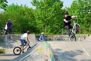 Das Bild zeigt Jugendliche mit ihren Fahrrädern auf dem Parcour des Skateplatzes in der Günther-Klotz-Anlage.