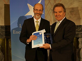 Der damalige Bürgermeister Klaus Stapf (l.) nimmt vom damaligen Umweltminister des Landes Baden-Württemberg, Franz Untersteller, die Urkunde zum "Leitstern Energieeffizienz 2014" entgegen.