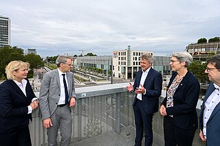 OB Mentrup, Staatssekretärin Zimmer, Professoren der Hochschule Karlsruhe und die Amtsleitung des Stadtbauamts stehen auf der Aussichtsplattform K-Punkt mit Blick auf die Kreuzung am Ettlinger Tor