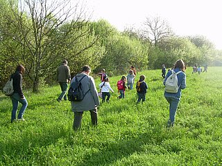 Das Bild zeigt Teilnehmende des Workshops Spuren lesen in Feld und Flur auf einer grünen Wiese.