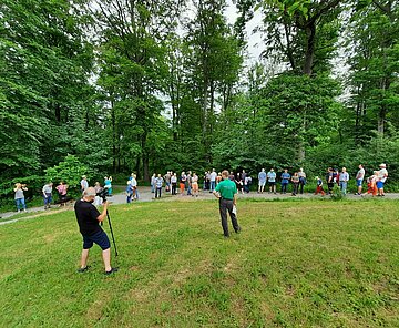 Das Bild zeigt Menschen bei einer Veranstaltung im Wald.