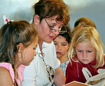 Ehrenamtliche Lesepatin liest Kindern vor.