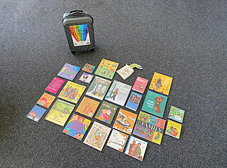 Der Regenbogenkinderbücherkoffer zusammen mit den Büchern die sich darin befinden