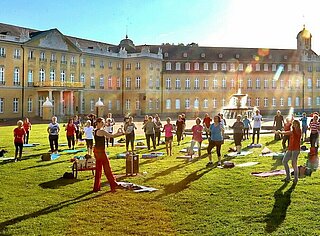 Menschen beim Sport auf der Wiese vor dem Karlsruhe Schloss