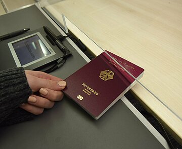 Händische Übergabe eines beantragten Reisepasses im Bürgerbüro