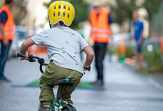 Kind fährt auf Straße mit Fahrrad