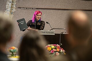 Alexandria Dritschler (Sprecherin queerKAstle) präsentiert den in Kooperation mit 20 Vereinen erstellten Forderungskatalog für ein queerfreundliches Karlsruhe.