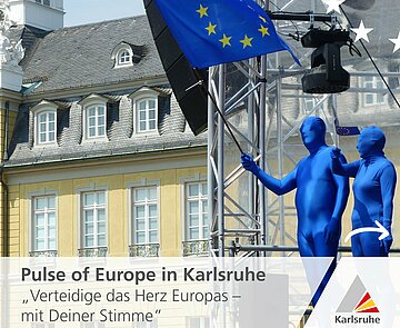 Zwei blau verkleidete Menschen stehen vor dem Karlsruher Schloss und schwenken eine Europaflagge