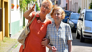 Das Bild zeigt eine Frau, die eine Seniorin begleitet.