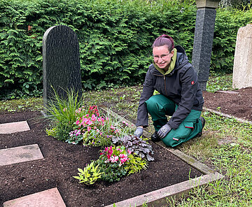 Junge Frau bepflanzt das Grab