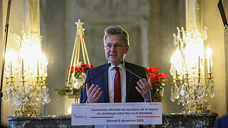 Karlsruhes Oberbürgermeister Dr. Mentrup bei seinem Grußwort mit hellen Leuchtern im Hintergrund