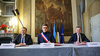 Die drei Oberbürgermeister Morhunov, Klein und Dr. Mentrup unterzeichnen nebeneinander sitzend die trilaterale Vereinbarung der drei Städte