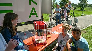 Am Stand der Hochschule Karlsruhe (HKA) können die Kinder Strom für eine Popcornmaschine erzeugen, indem sie auf zwei Ergometern in die Pedale treten.