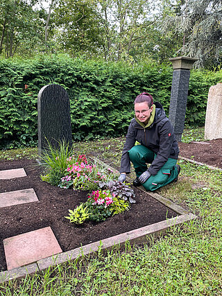 Junge Frau bepflanzt das Grab
