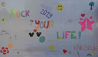 Das Bild zeigt ein Plakat der Initiative Rock Your Life anlässlich eines Sommerfests in Karlsruhe.