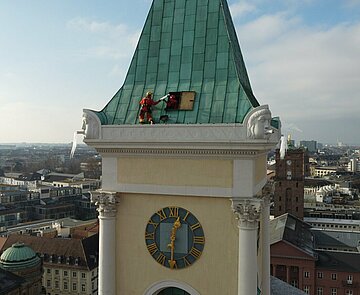 Drei Höhenrettungskräfte lösen Eiszapfen auf dem Dach der Stadtkirche.
