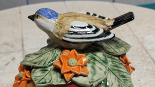 Das Bild zeigt eine bunte Kugel mit einem Vogel aus Keramik.